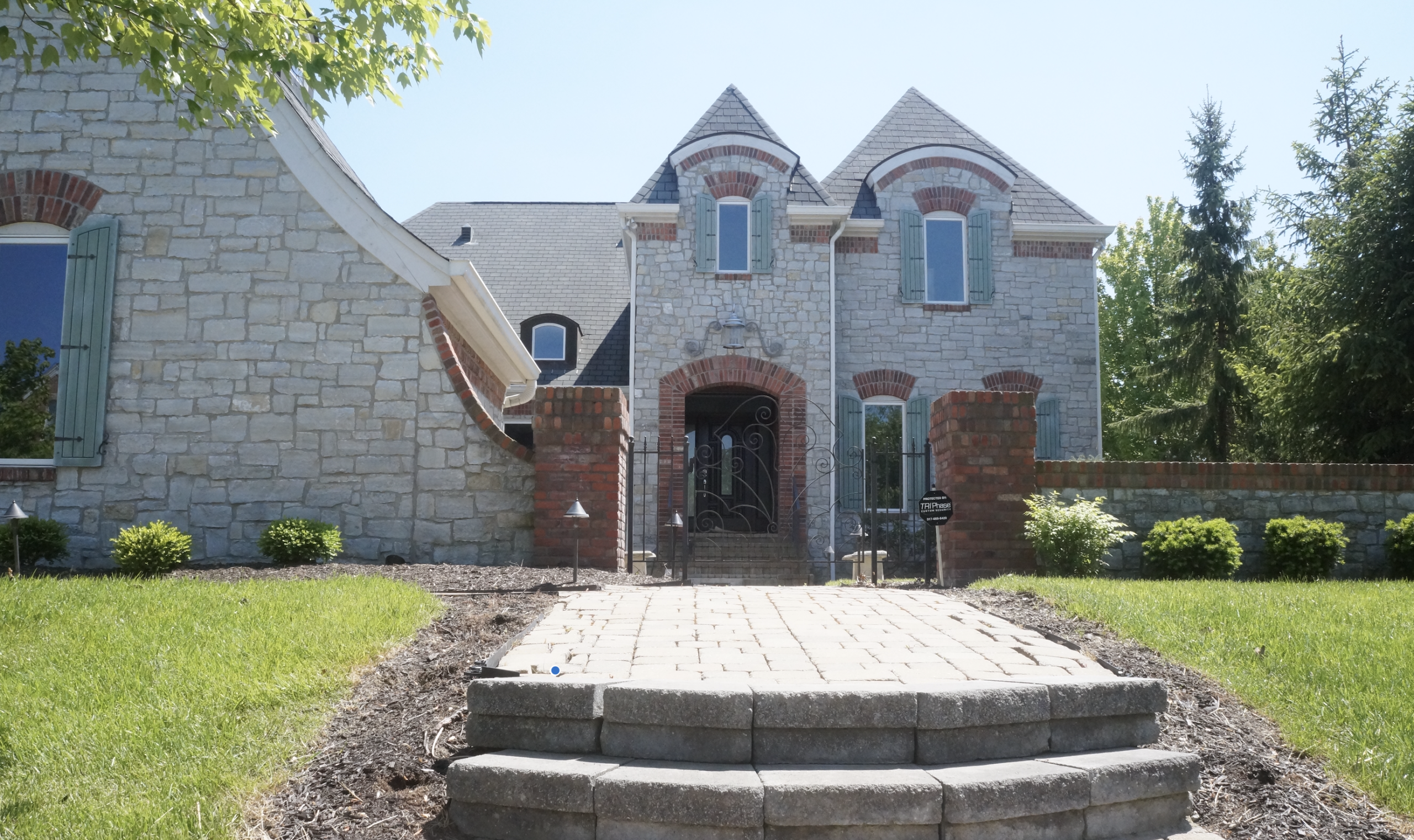 Marvin Essential replacement windows on a stone and brick home with green shutters in Carmel, Indiana.